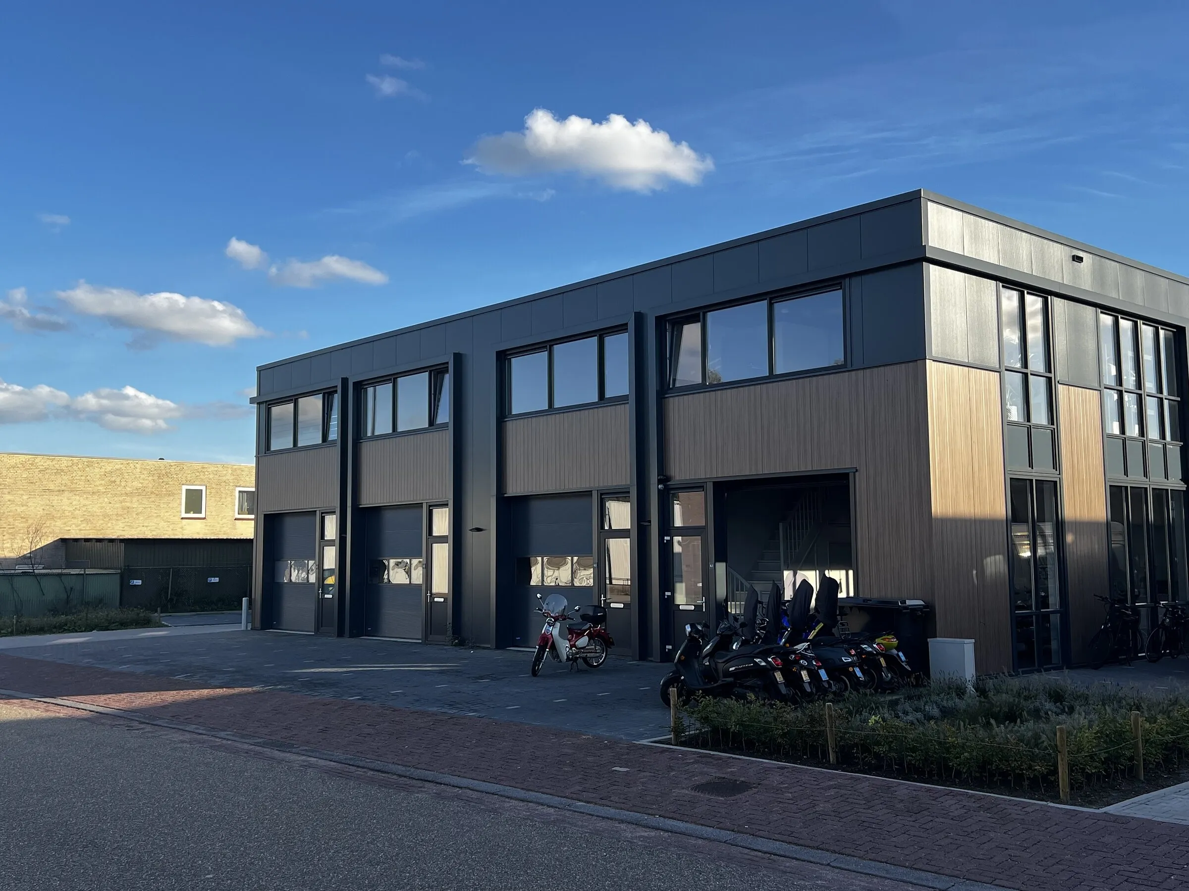 Gevel van Hoekman Scooters unit 6.1 met open werkplaatsdeur, scooters en servicebus